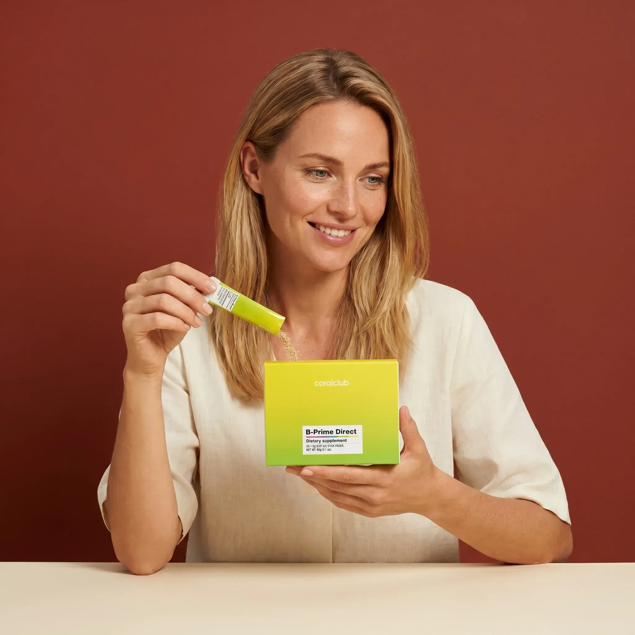 B-Prime Direct lifestyle image with a woman holding the product box and applying the serum.