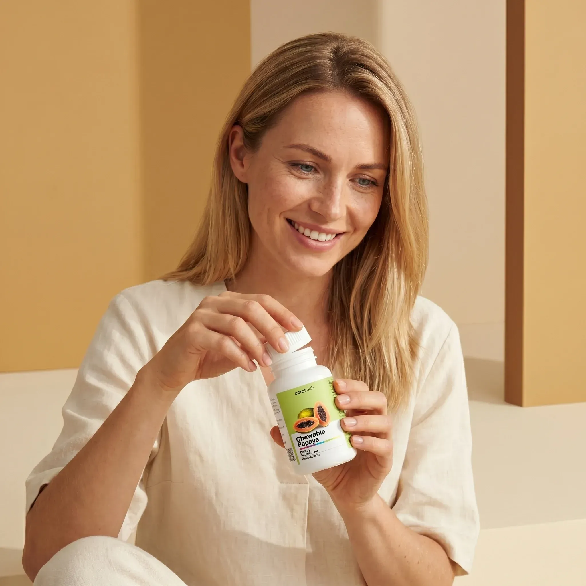 Woman enjoying Chewable Papaya supplement, holding the bottle in a bright, minimalistic setting.
