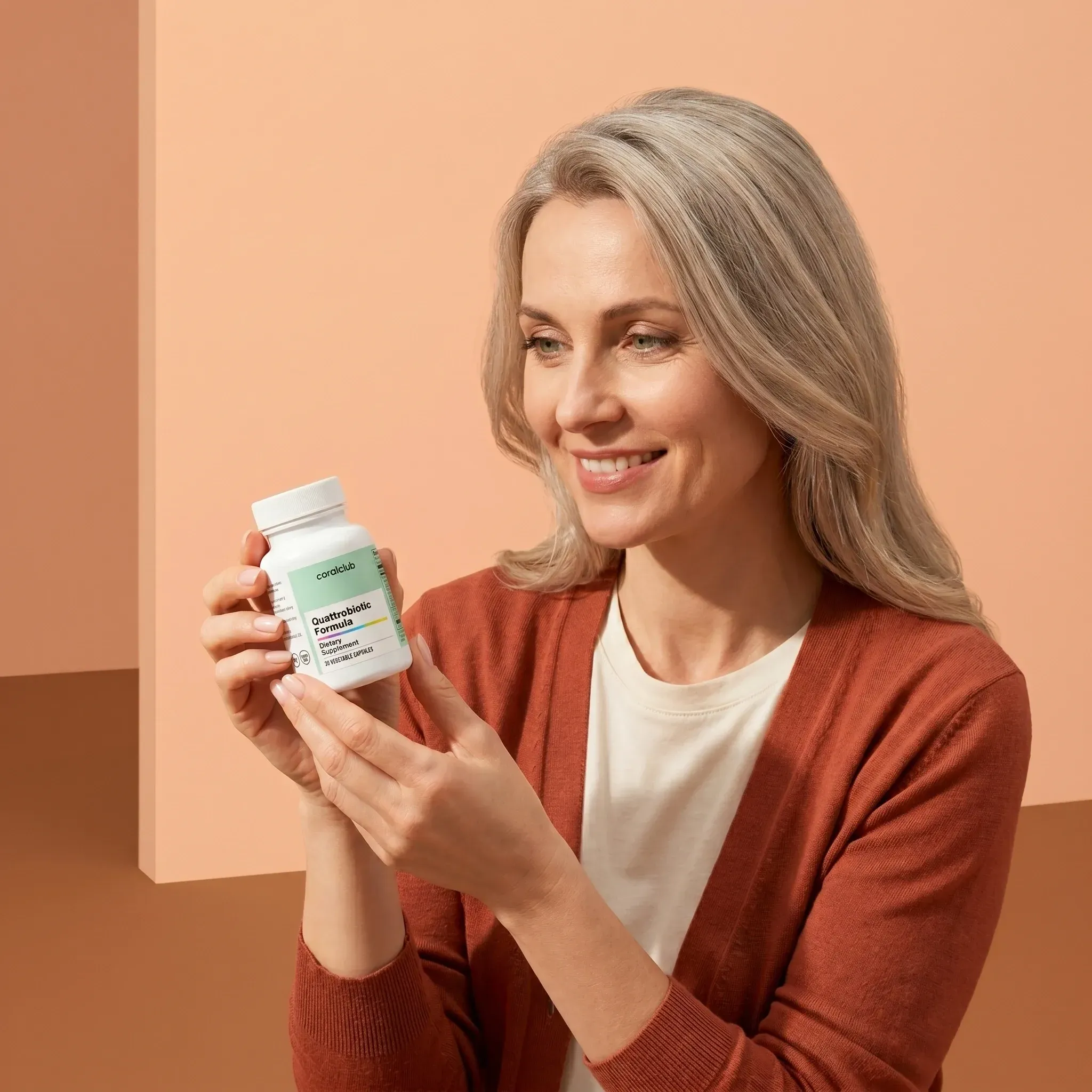 Quattrobiotic Formula lifestyle image with a woman holding the supplement bottle against a soft peach background.